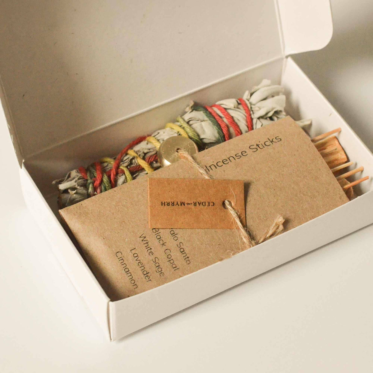 Open Burning Ritual Kit box showing a tied white sage bundle, palo santo and kraft incense sleeve