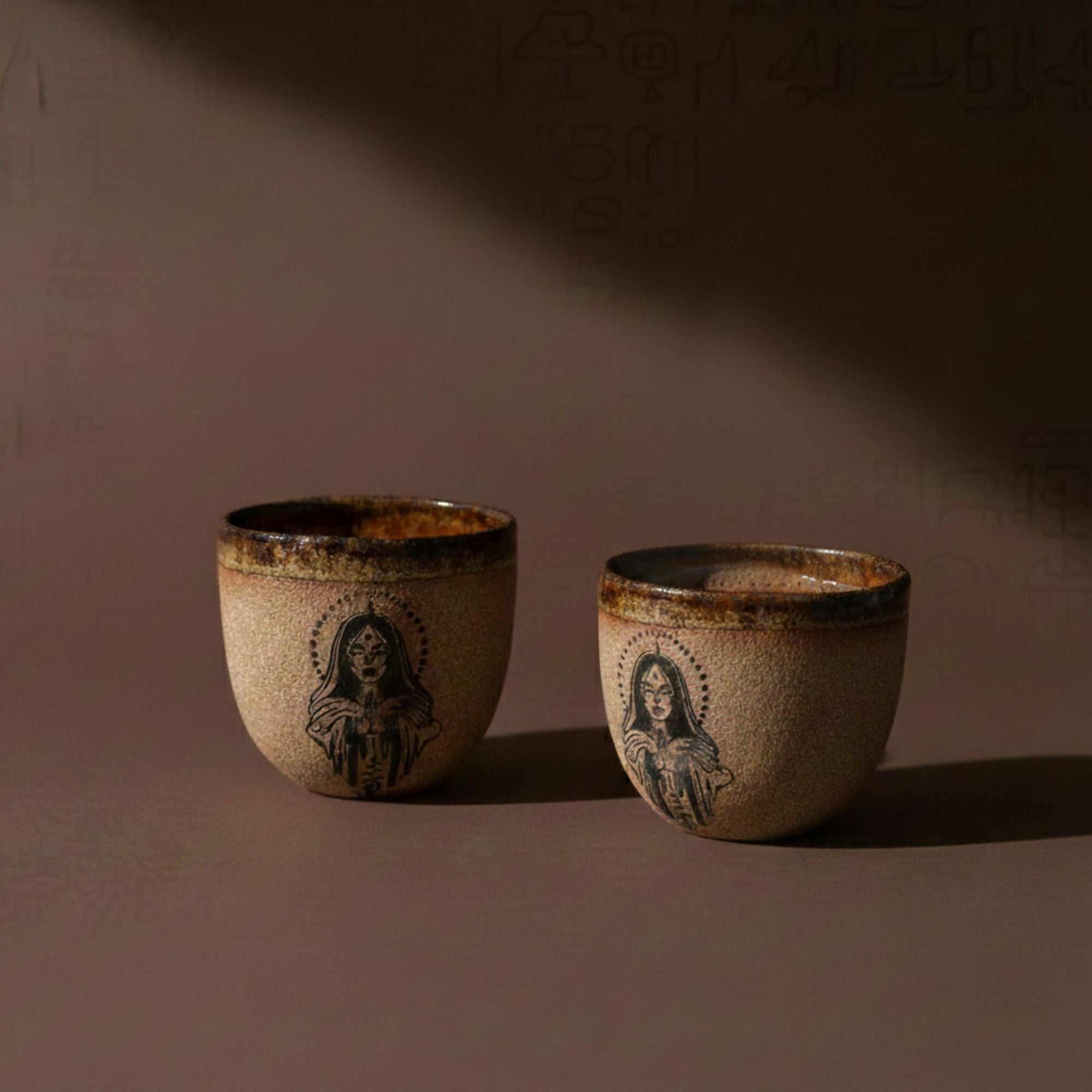 Two ceramic cups with artistic designs on a brown background