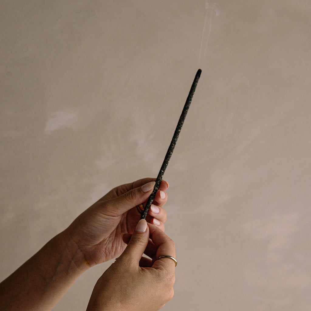Hand holding a black pen against a beige background