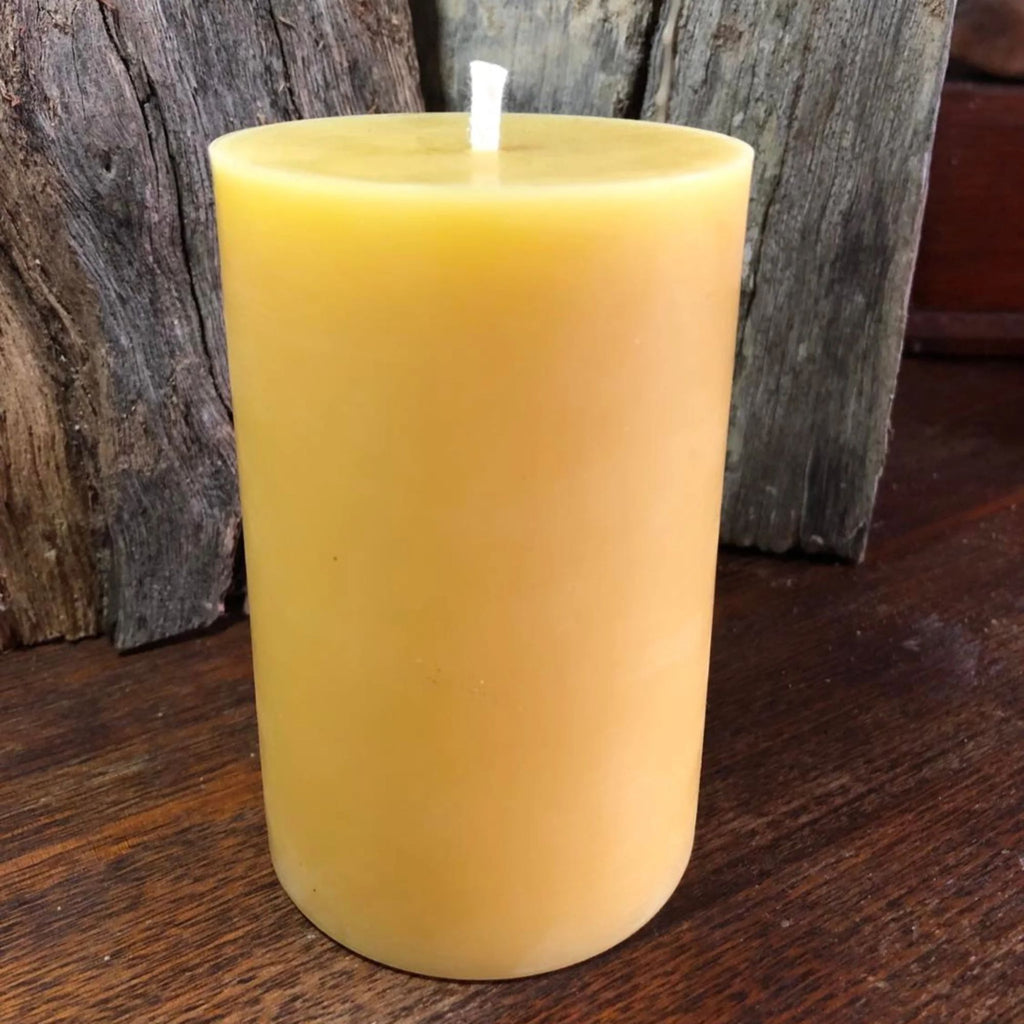 Yellow natural 100% beeswax candle on a wooden surface with a rustic background