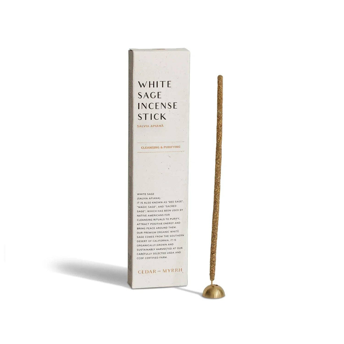 White Sage incense stick standing in a small brass holder beside its tall cream box