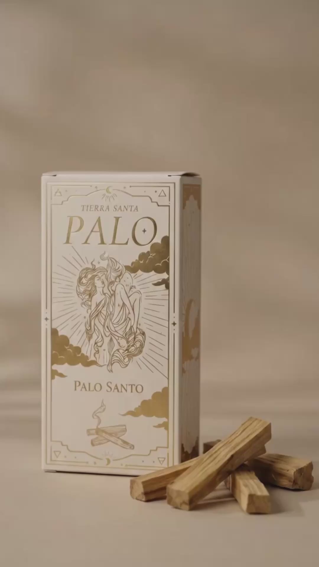 video of packaging of palo santo, showing a hand come into frame and showing a stick of palo santo that is lit by candle light, blown out, and the smudging smoke of the incense is shown